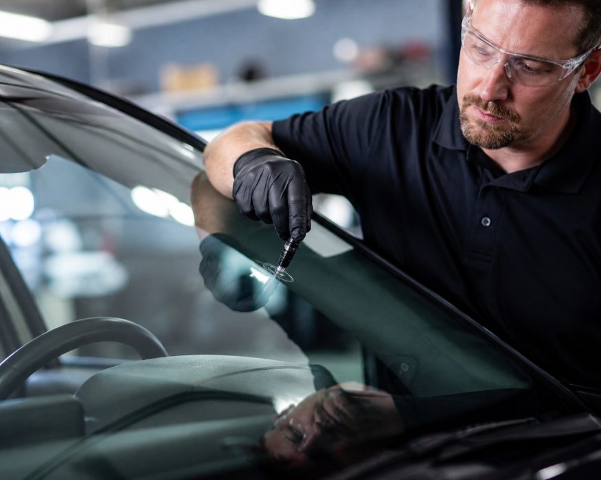 Auto glass technician injecting resin into a windshield chip